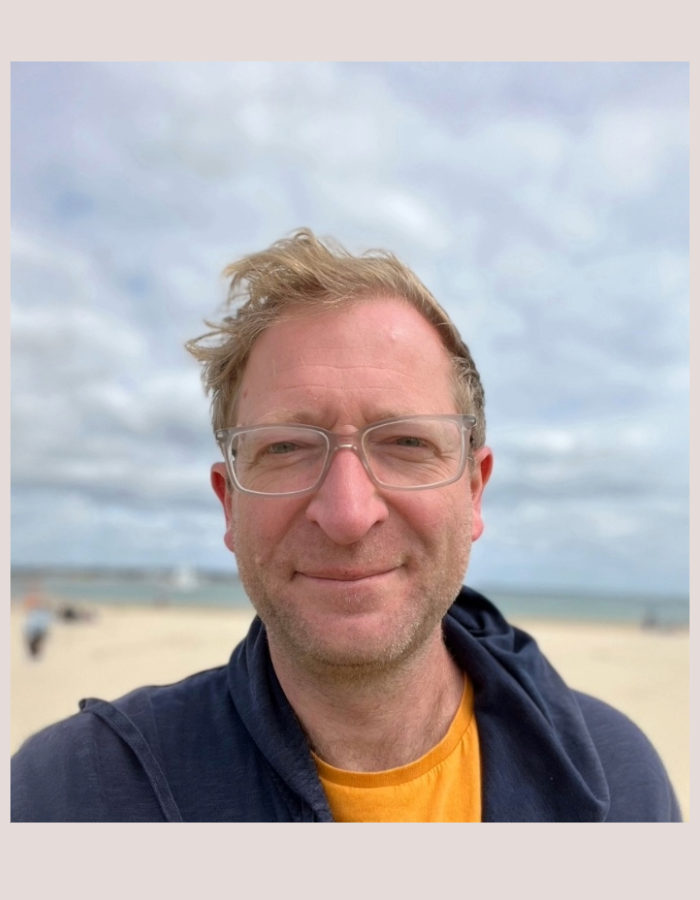 Headshot of Camp Digital 2026 speaker Dan Barrett. Dan has short blonde hair and clear framed glasses