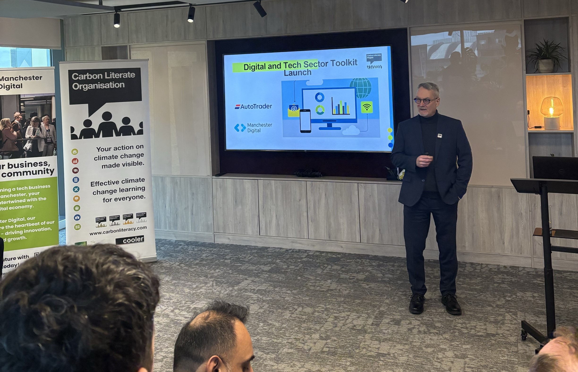 Dave Coleman, Managing Director of The Carbon Literacy Project stands in front of a seated audience. Onscreen behind him is a slide which reads "Digital and Tech Sector Toolkit Launch"