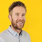 A headshot of Simon Wissink, a white man with ginger hair and a ginger beard.