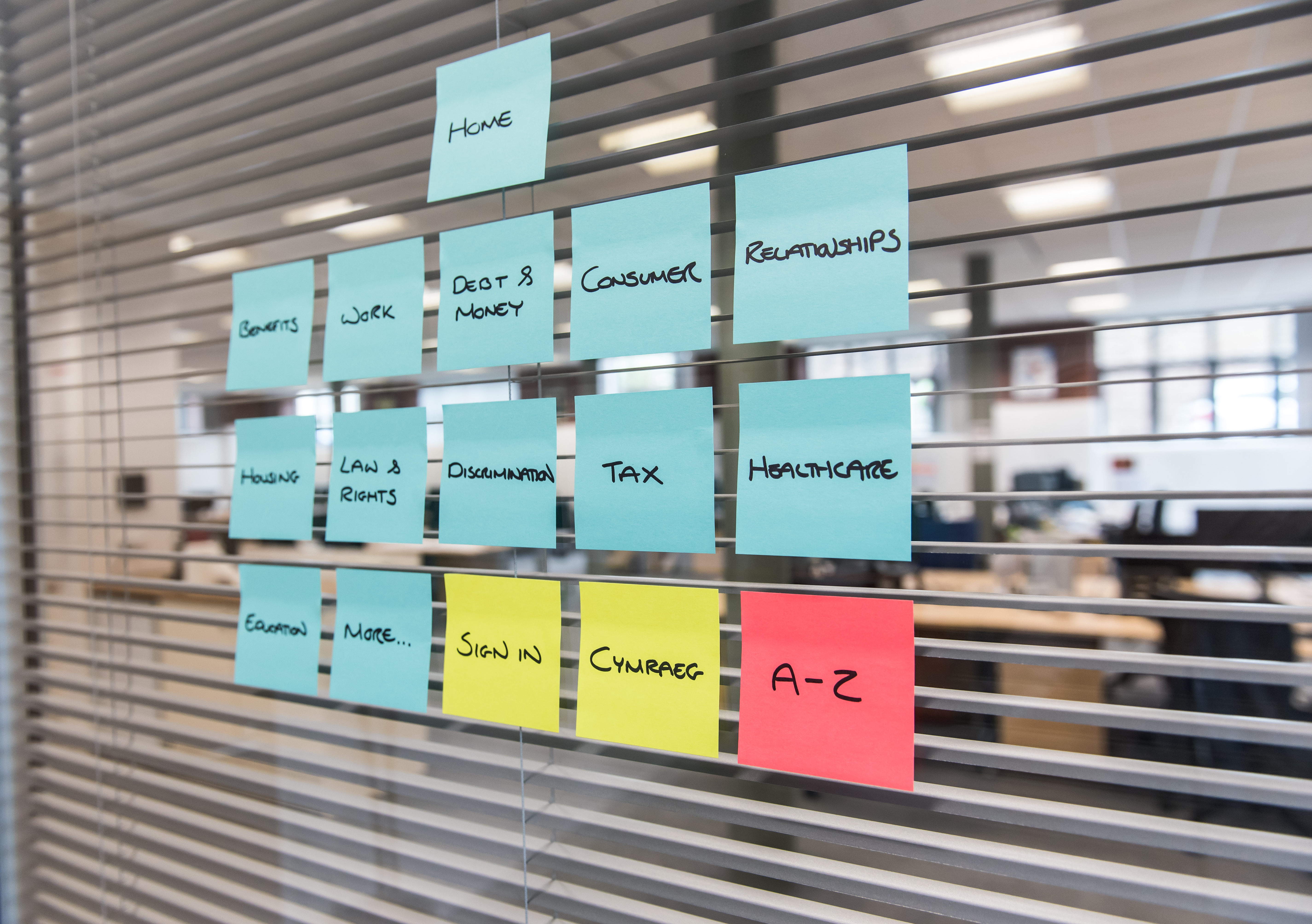 Post-it notes stuck on a glass wall, with an office in the background
