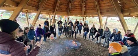 Our team gathers round a fire pit in the woods