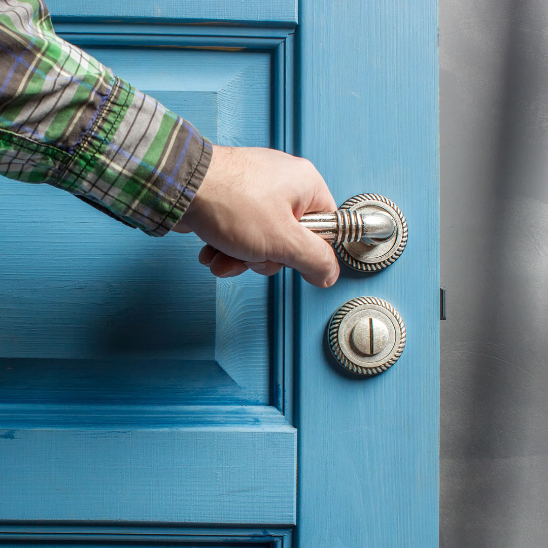 Picture, in close up, of a hand on a door handle. The door is being opened. Or closed.
