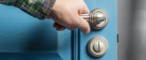 Picture, in close up, of a hand on a door handle. The door is being opened. Or closed.