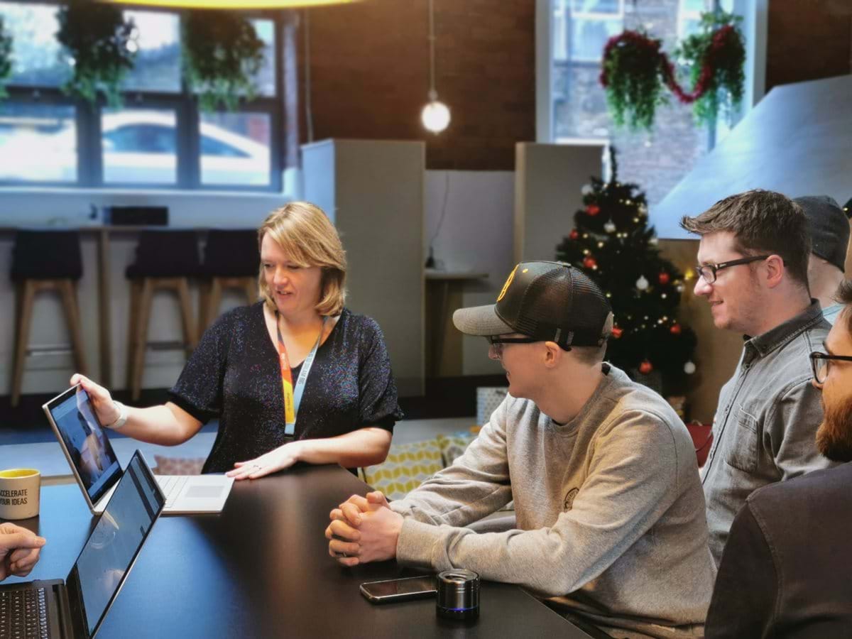 Three people stood around a laptop