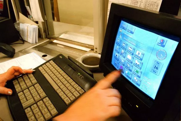 A person using a computer (a model from the 1990s) pointing at the screen