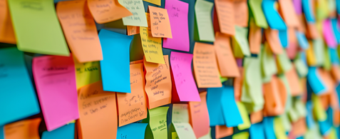 A wall of colourful post it notes, which each have writing on, though it's illegible.