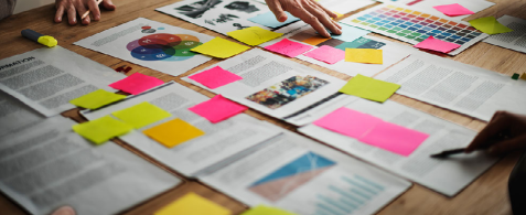 Documents and charts on a table with post it notes stuck on the front. 