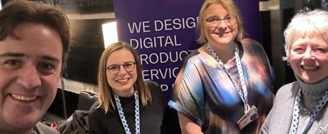 Chris, Burcu, Rachel and Elizabeth smile at the camera in front of a Nexer Digital banner