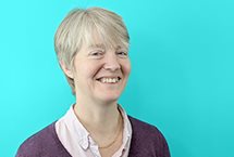 A headshot of Caroline McKillop - a smiling white woman with grey short hair.