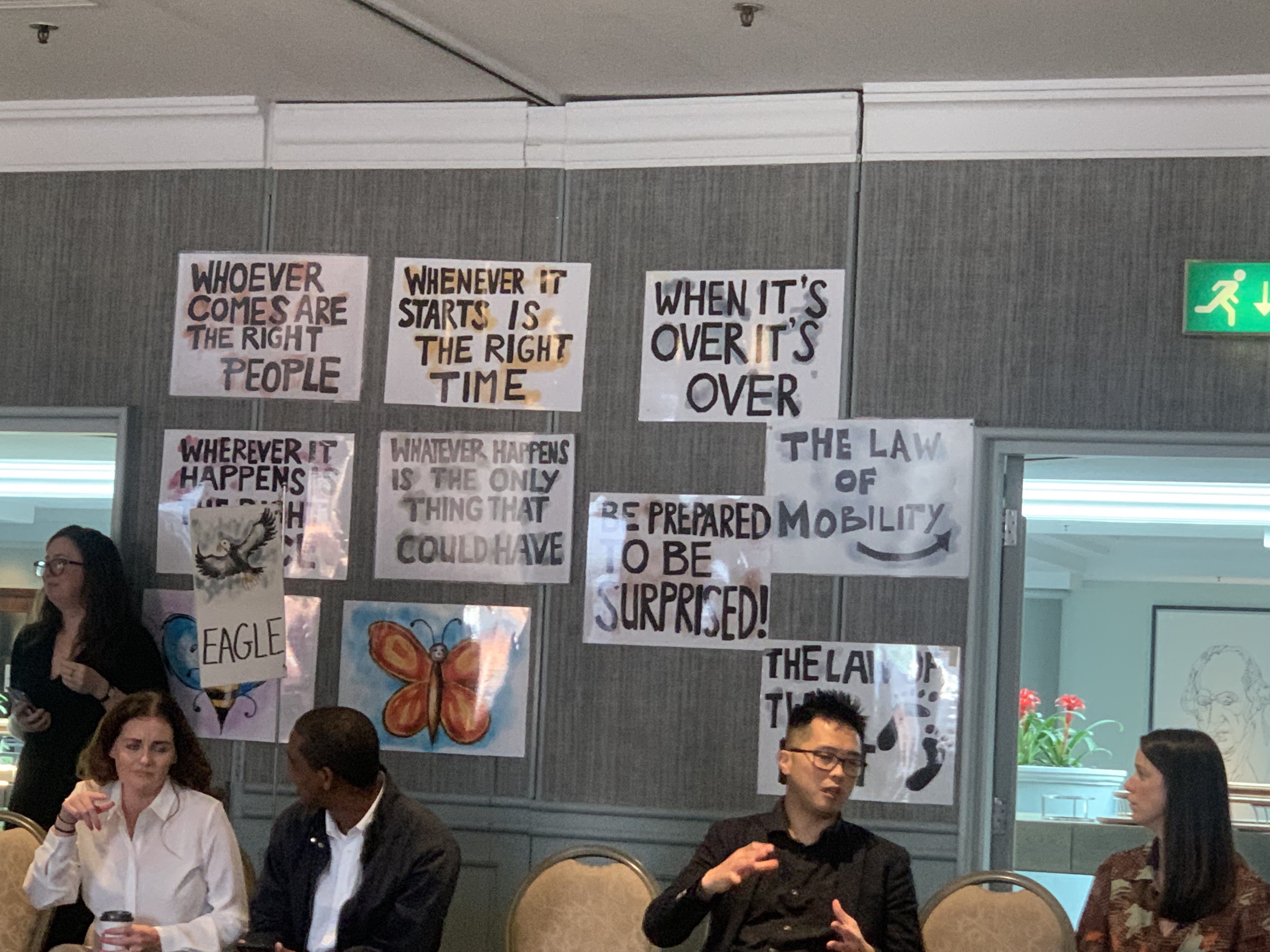 Seated people in discussion, with posters behind them featuring different ideas around health research