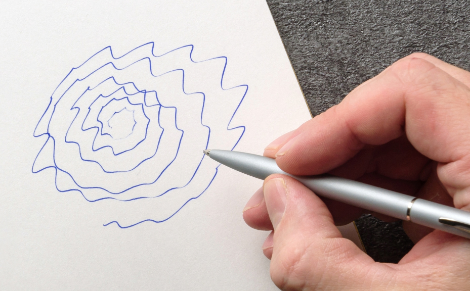 A hand drawing a jagged spiral, showing the effects of Essential Tremor.