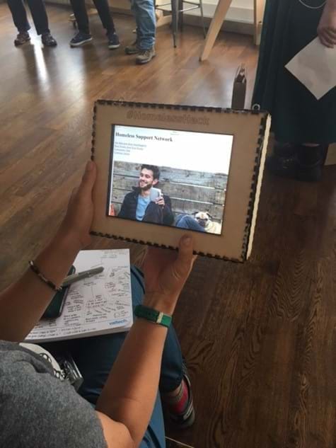 A white woman holding a a tablet, with a prototype of a homeless hack solution.