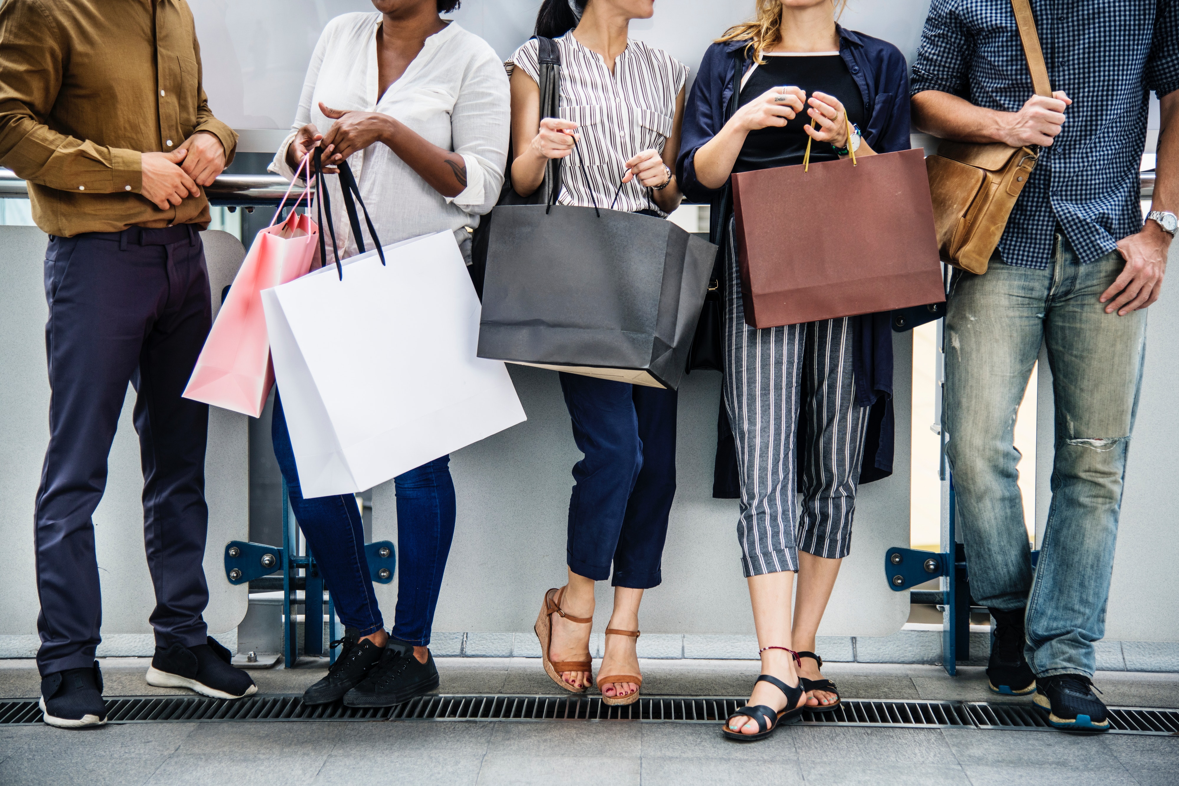 A Line Of People All Standing With Shopping Bags