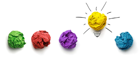 A line of screwed up paper post it notes. A yellow one has been presented as a lightbulb, standing out from the rest of the lineup.