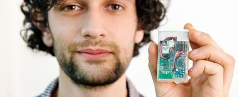 Tim Omer holding up part of the diabetes monitoring kit he built himself, which looks like a small Tic Tac box.