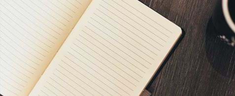 An open diary notebook resting on a dark wooden table