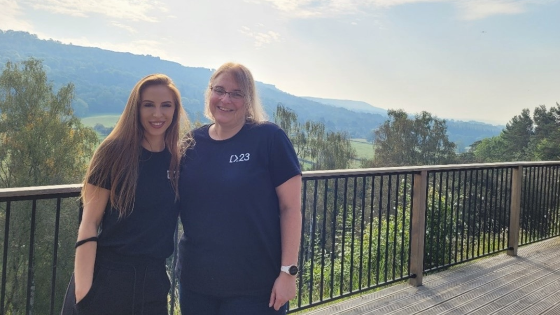 Delia and Rachel standing together and smiling, with green hills in the background 