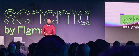 An audience seated in front of a stage with a speaker standing, and a slide reading "schema by Figma"