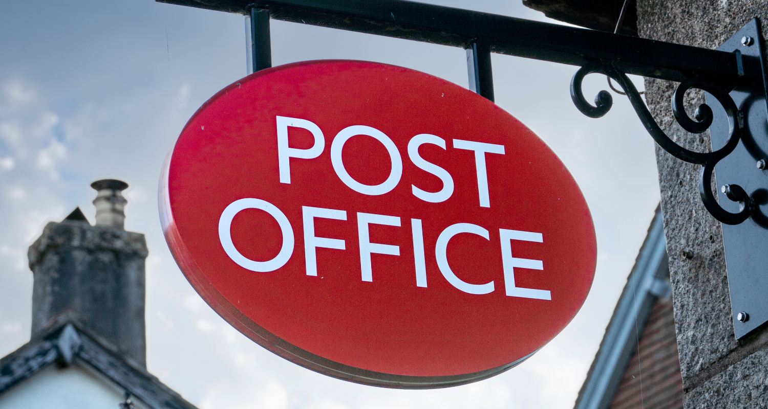 A Post Office sign, with blue sky visible behind it 