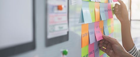A close up of hands sticking post-it notes to a board