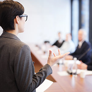 The back of a female giving a talk to people in front of her